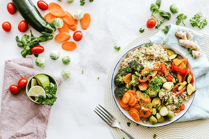A flat-lay photograph of vegetable salad on a plate with a fork on the side