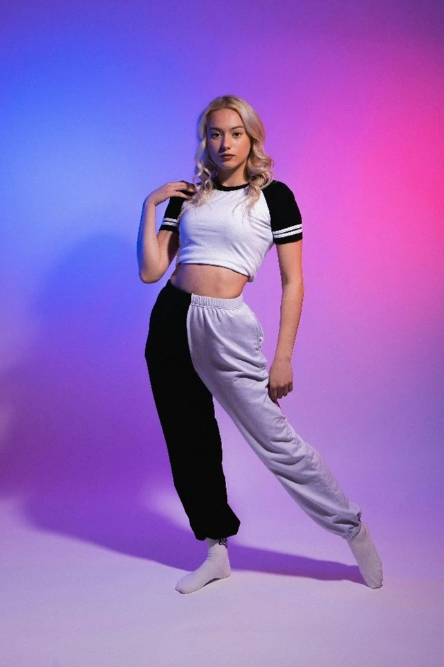 A woman posing wearing a white cropped T-shirt and sweatpants