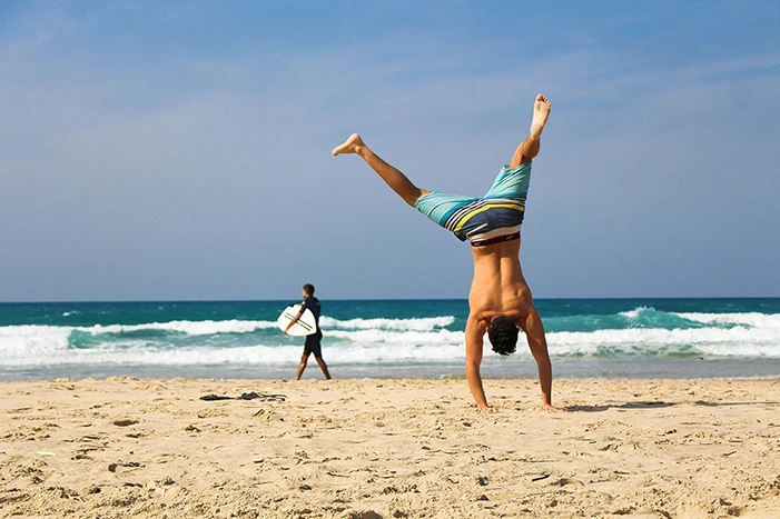 A man doing a handstand on the beach