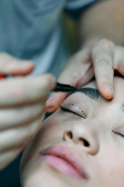 Close-up of a cosmetic professional marking a patient's eyelid before a procedure.