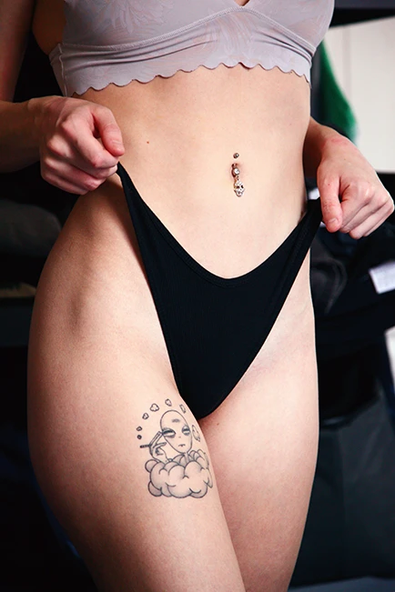 Woman in underwear showing a tattoo on her hip.