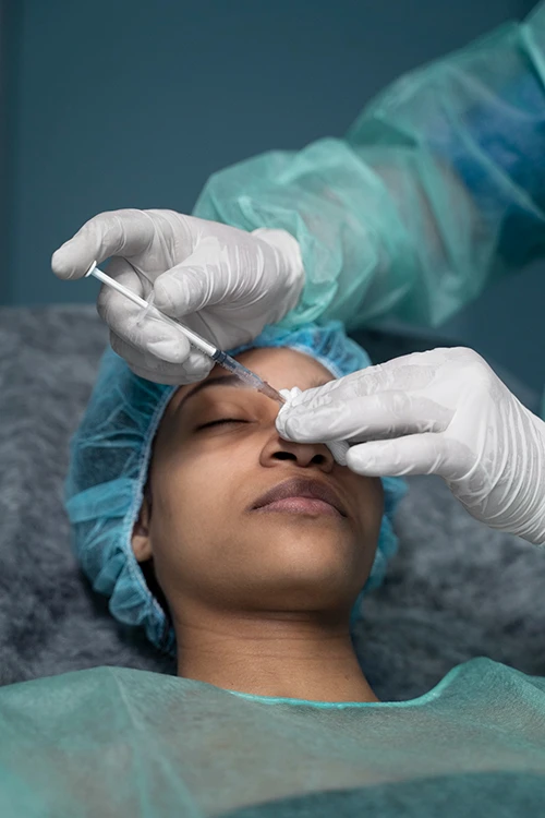 A surgeon administering anaesthesia to a patient before performing rhinoplasty 