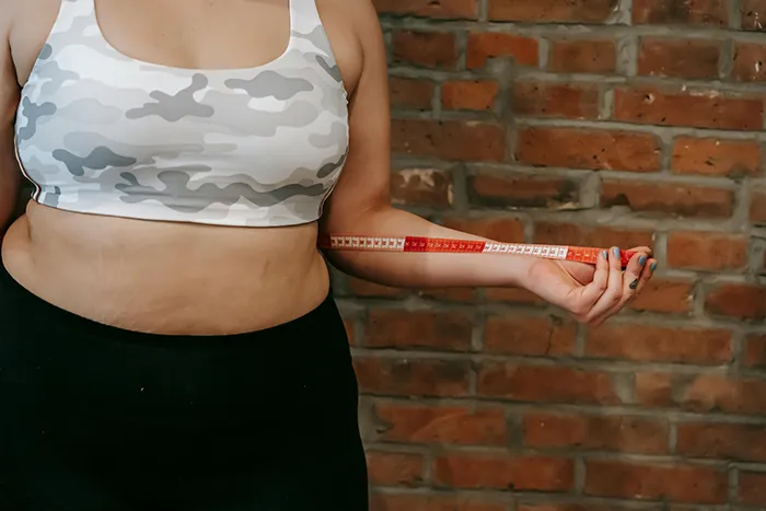 A person holding a measuring tape to their waist