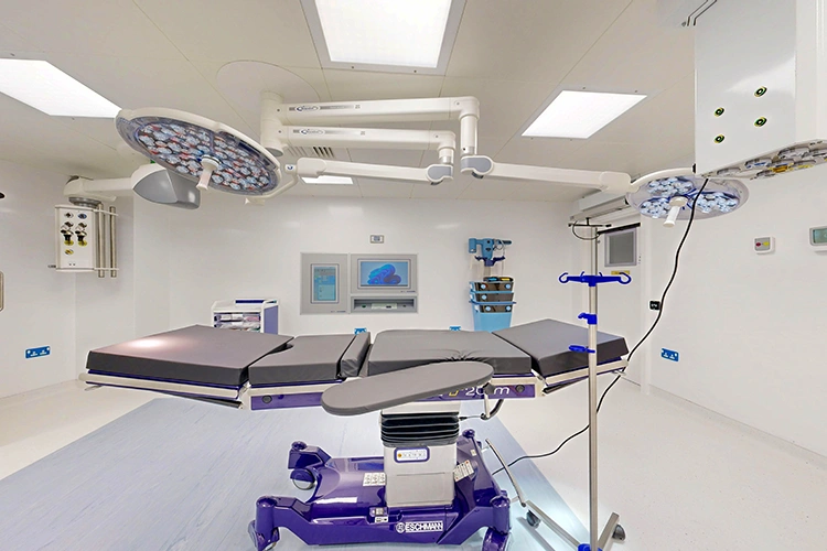 Sterile operating theatre at London Private Hospital with adjustable operating table, ceiling-mounted LED surgical lights and anaesthesia equipment.