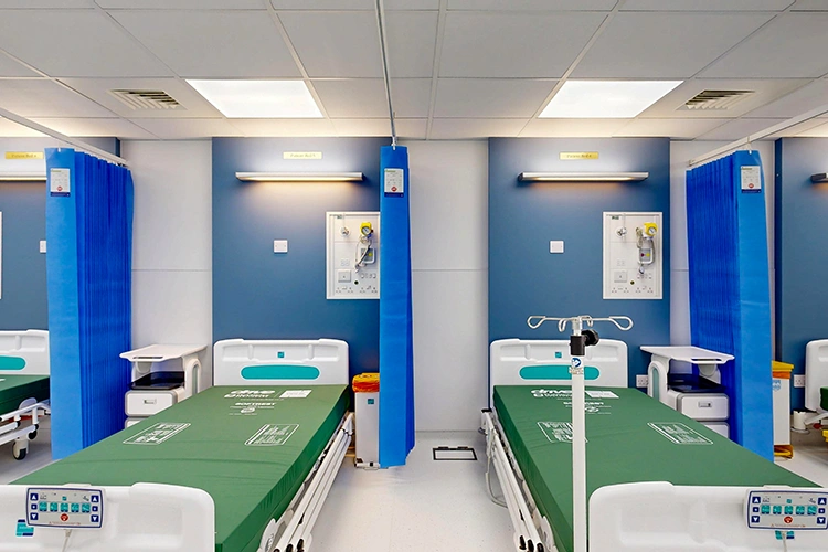 Recovery ward bays at London Private Hospital with adjustable beds, blue privacy curtains, and wall-mounted oxygen and suction units.